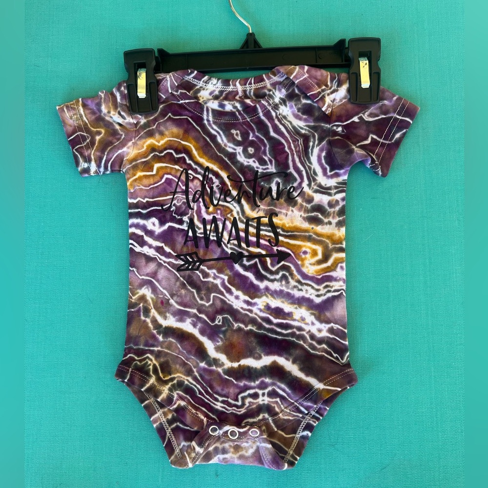 Hand dyed onesie with graphic “adventure awaits” print.